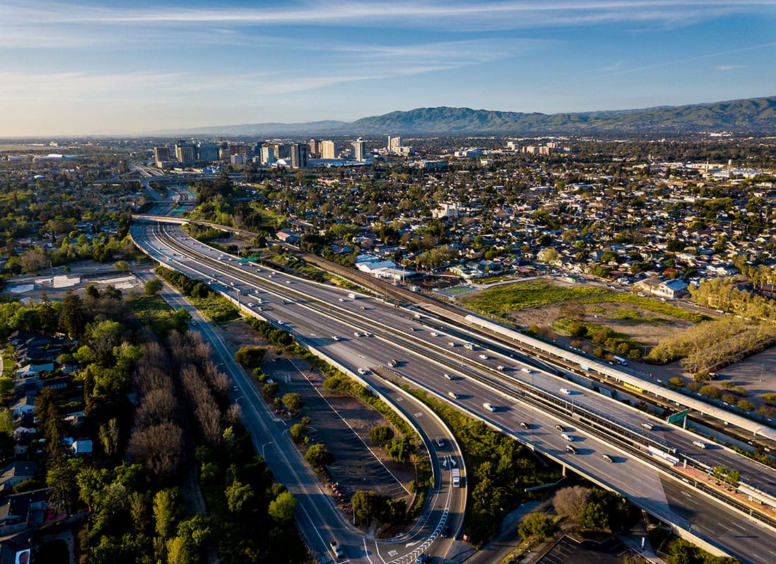 Contact - Aerial View of Highways Homes Surrounded by Green Trees and Commercial Buildings in the Distance in Silicon Valley California