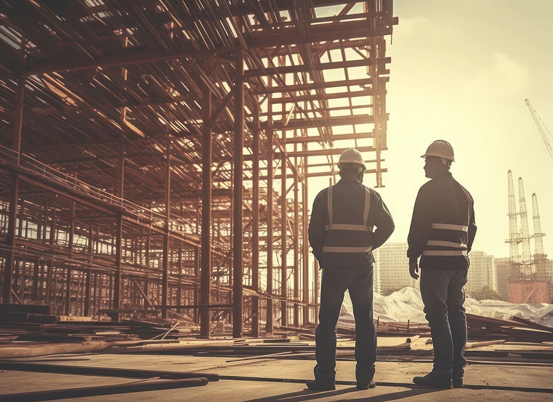 Insurance by Industry - Rear View of Two Male Contractors Standing Next to a New Commercial Building Construction Project in a City